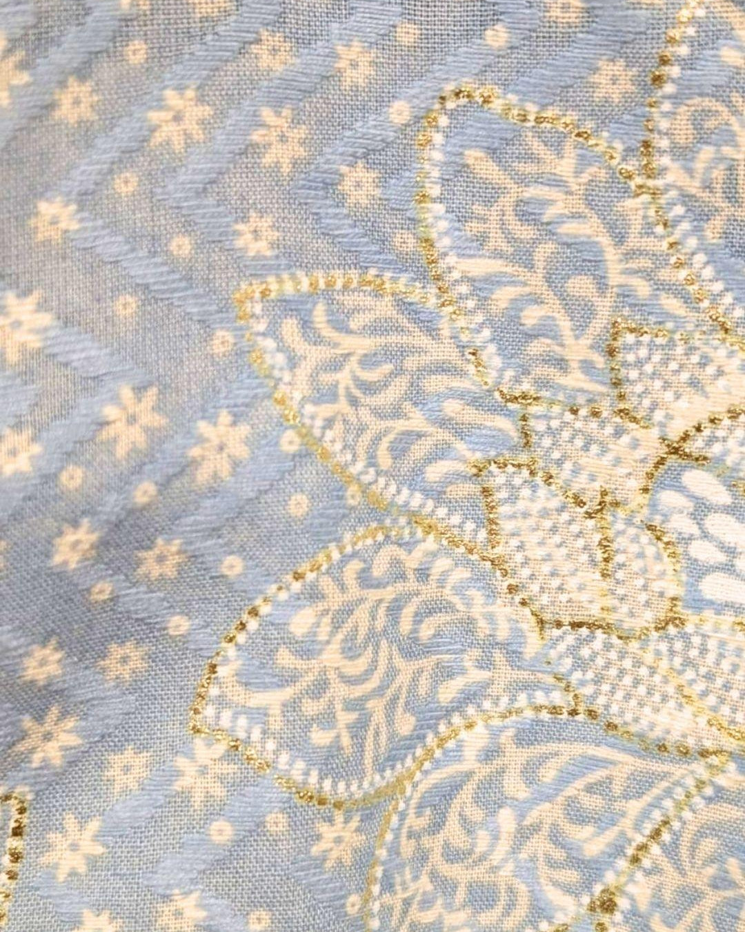 Close-up of blue cotton kurta fabric with intricate cream and gold floral embroidery and tiny scattered motifs. - Nimbu