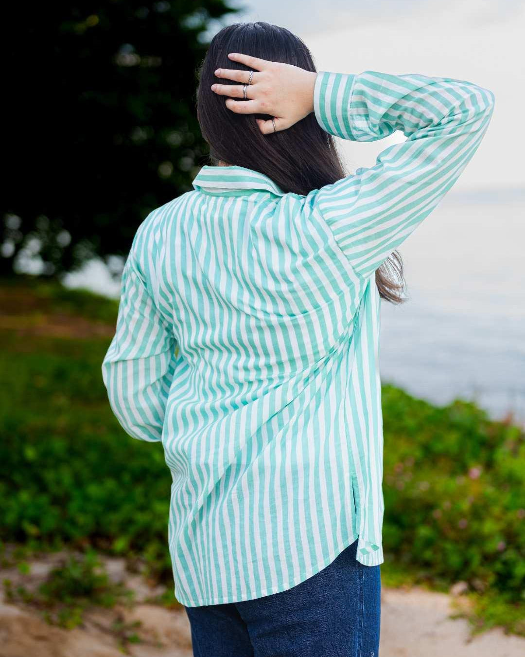 Person wearing a green and white striped shirt outdoors with a blurred background