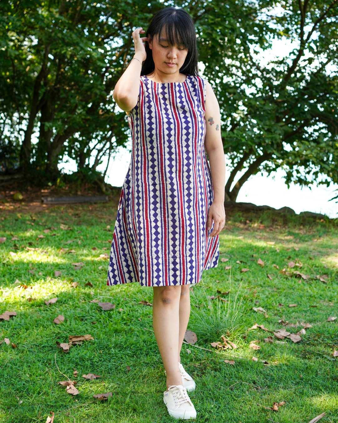 Women's sleeveless A-line dress with vertical desert stripe pattern in azure and white, made from sustainable cotton.