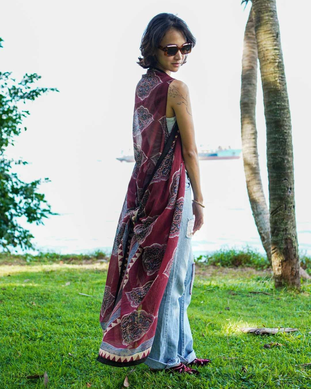 Vintage maroon sustainable cotton kimono with geometric print, sleeveless, flowing style, worn over jeans by a woman.