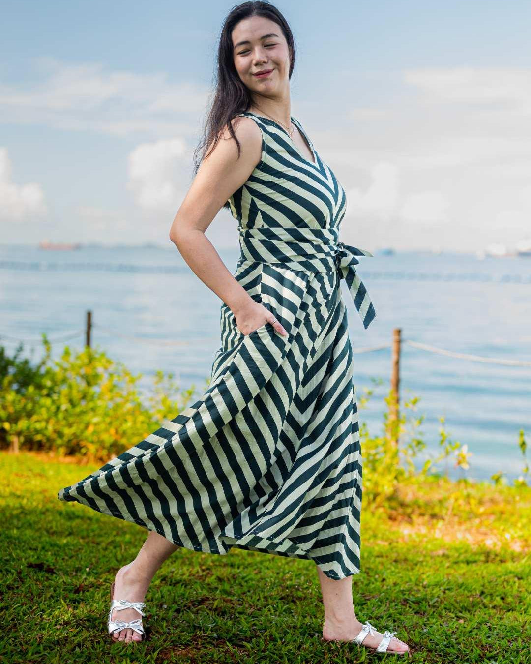 Green and white striped sustainable cotton women’s midi dress with obi belt and side pockets.