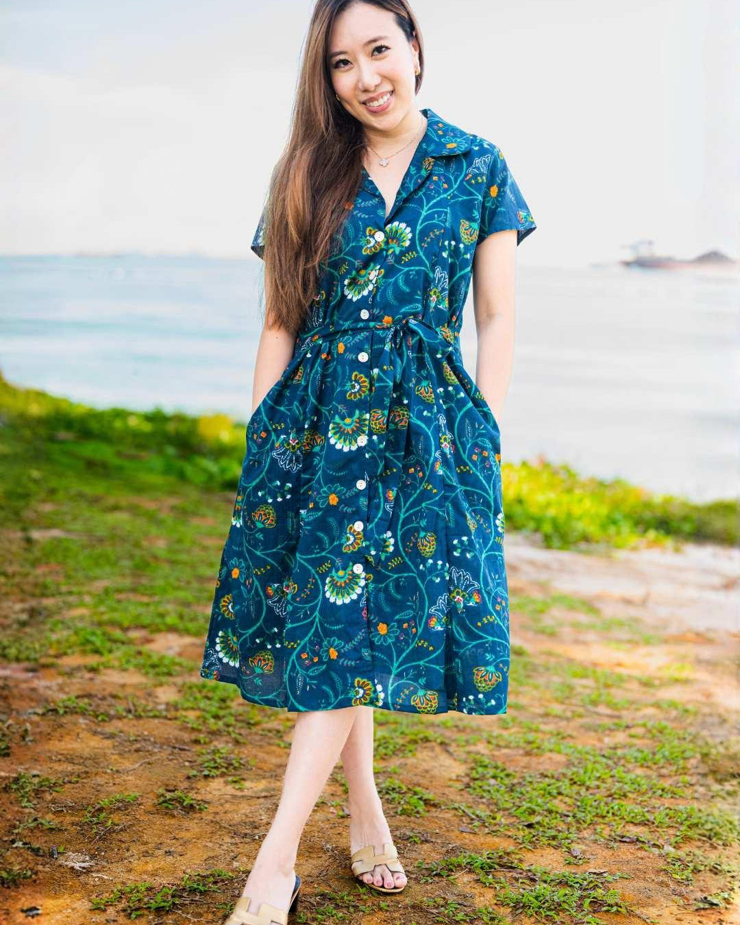 Woman wearing a blue floral dress standing outdoors with a natural background