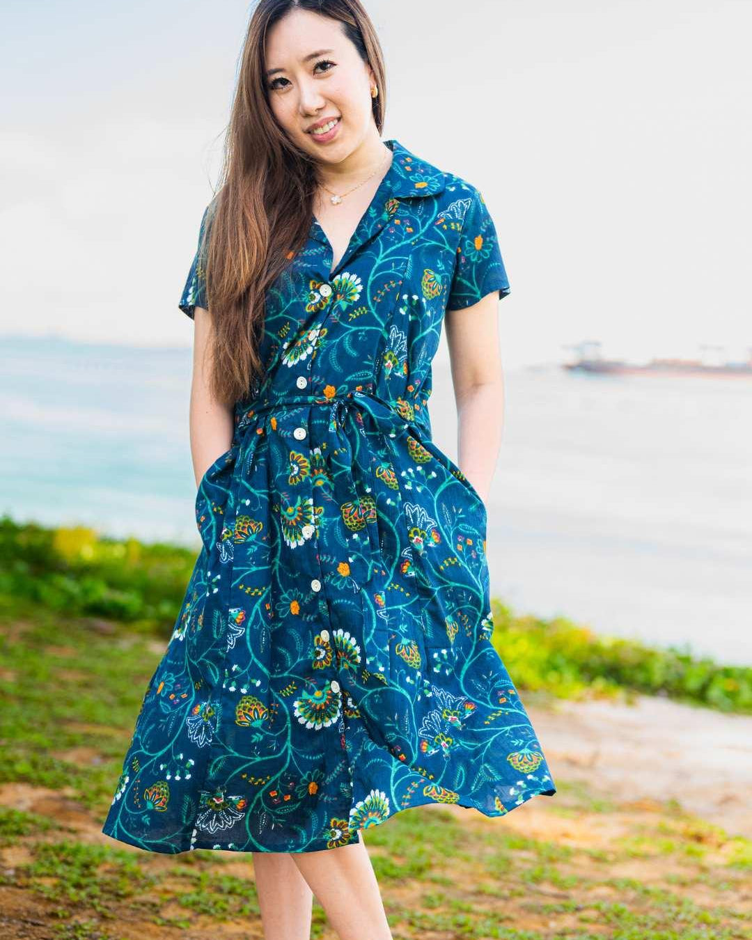 Woman wearing a blue floral dress standing outdoors with a blurred background
