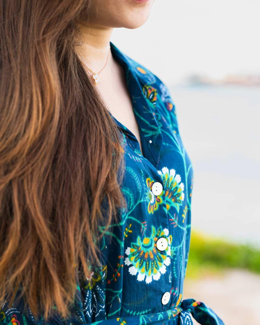 Woman wearing a blue floral dress with a blurred outdoor background