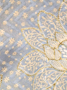 Close-up of blue cotton kurta fabric with intricate cream and gold floral embroidery and tiny scattered motifs. - Nimbu