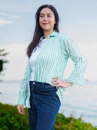 Woman wearing a green and white striped shirt with a blurred natural background