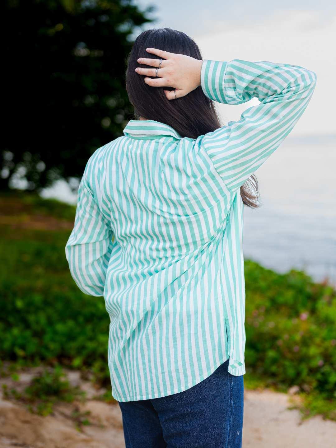 Person wearing a green and white striped shirt outdoors with a blurred background