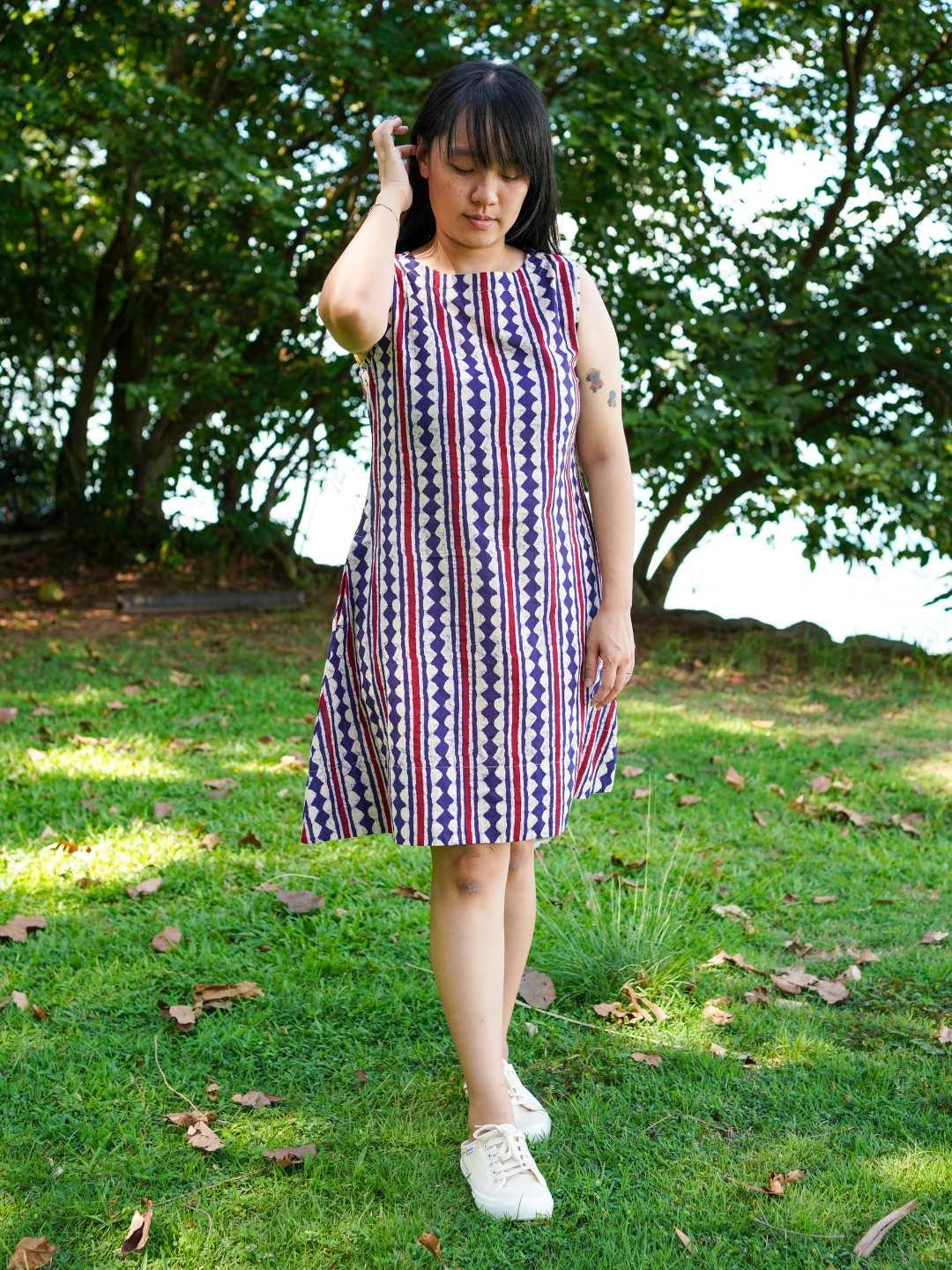 Women's sleeveless A-line dress with vertical desert stripe pattern in azure and white, made from sustainable cotton.