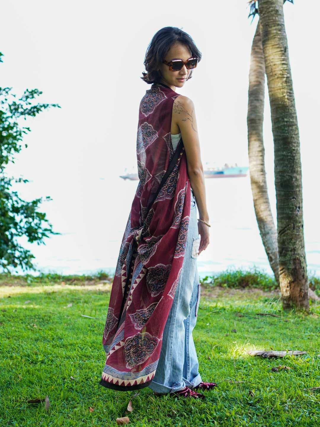 Vintage maroon sustainable cotton kimono with geometric print, sleeveless, flowing style, worn over jeans by a woman.