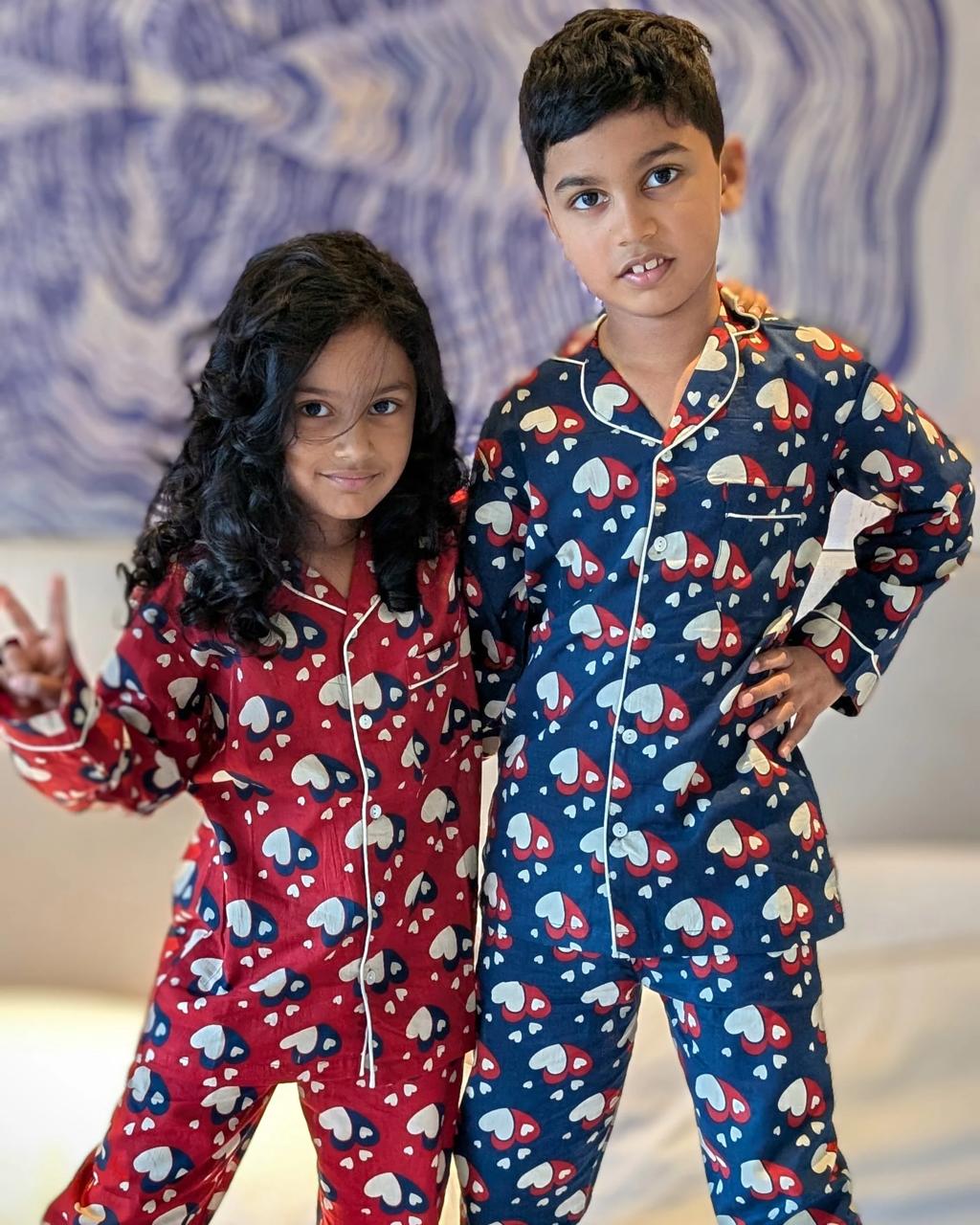 Two children wearing matching pajamas with a pattern of hearts and stars.
