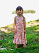 Girls' sustainable cotton long dress in rosy pink with tropical floral print, sleeveless and tiered design.