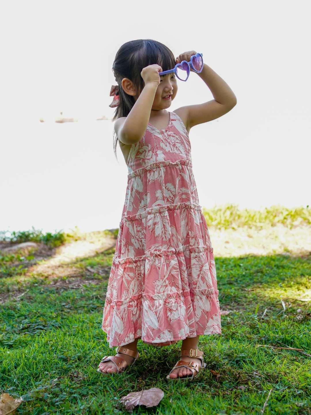 Girls long sleeveless rosy pink cotton dress with tropical leaf print, designed sustainably for casual wear.