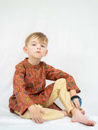 Boys’ coral cotton kurta pajama with a handcrafted gold floral print and cream trousers. - Nimbu