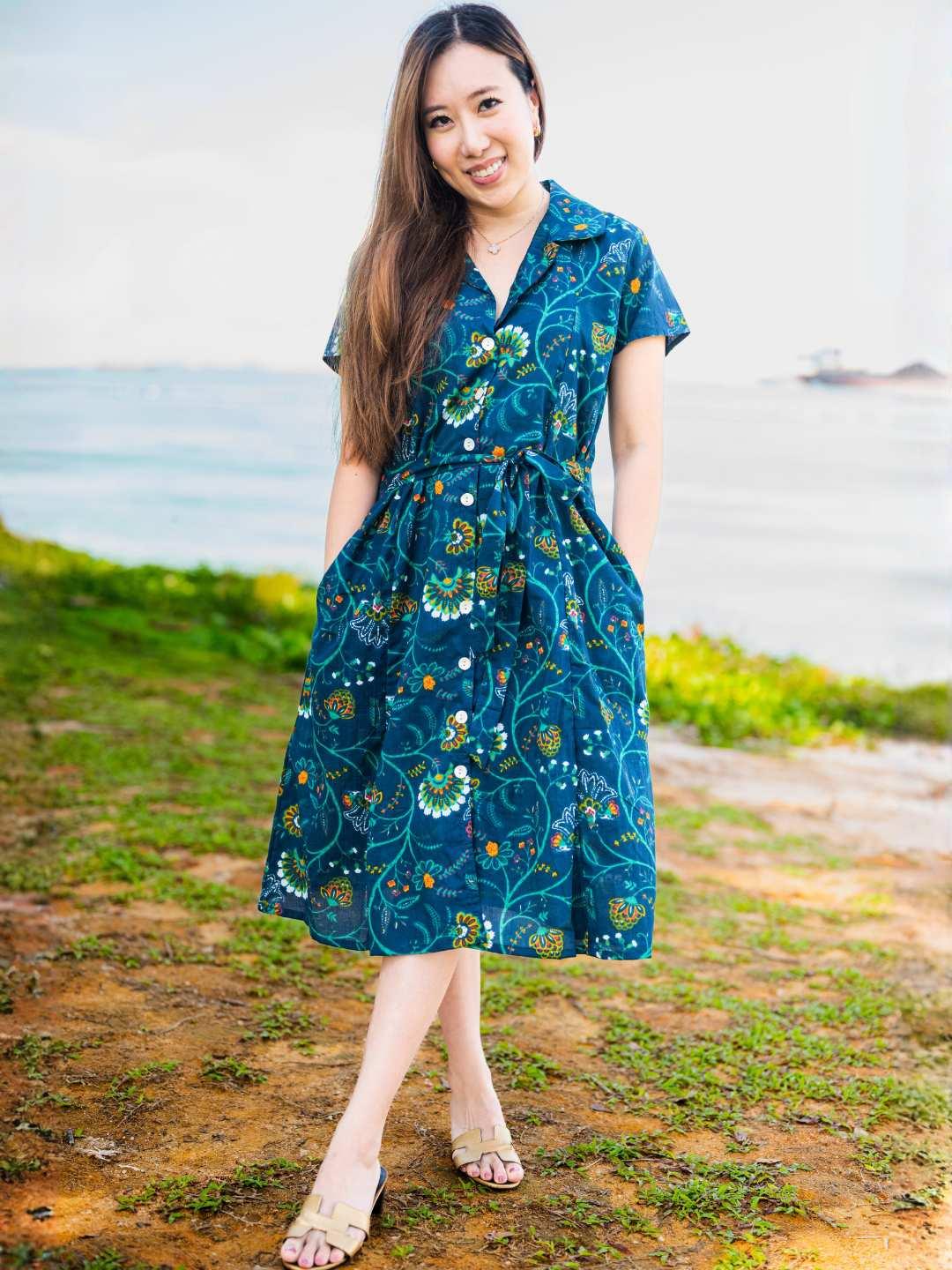 Woman wearing a blue floral dress standing outdoors with a natural background