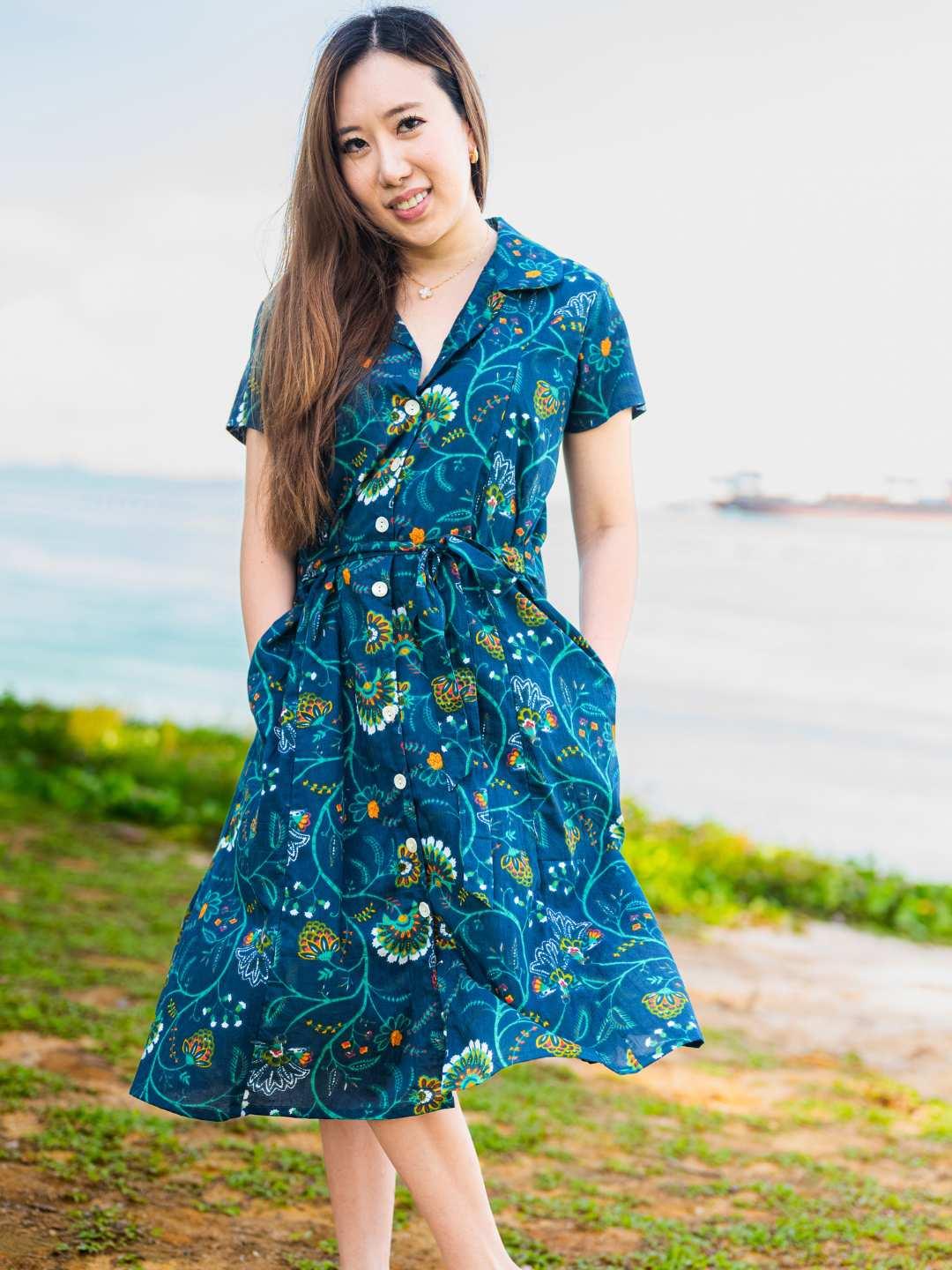 Woman wearing a blue floral dress standing outdoors with a blurred background