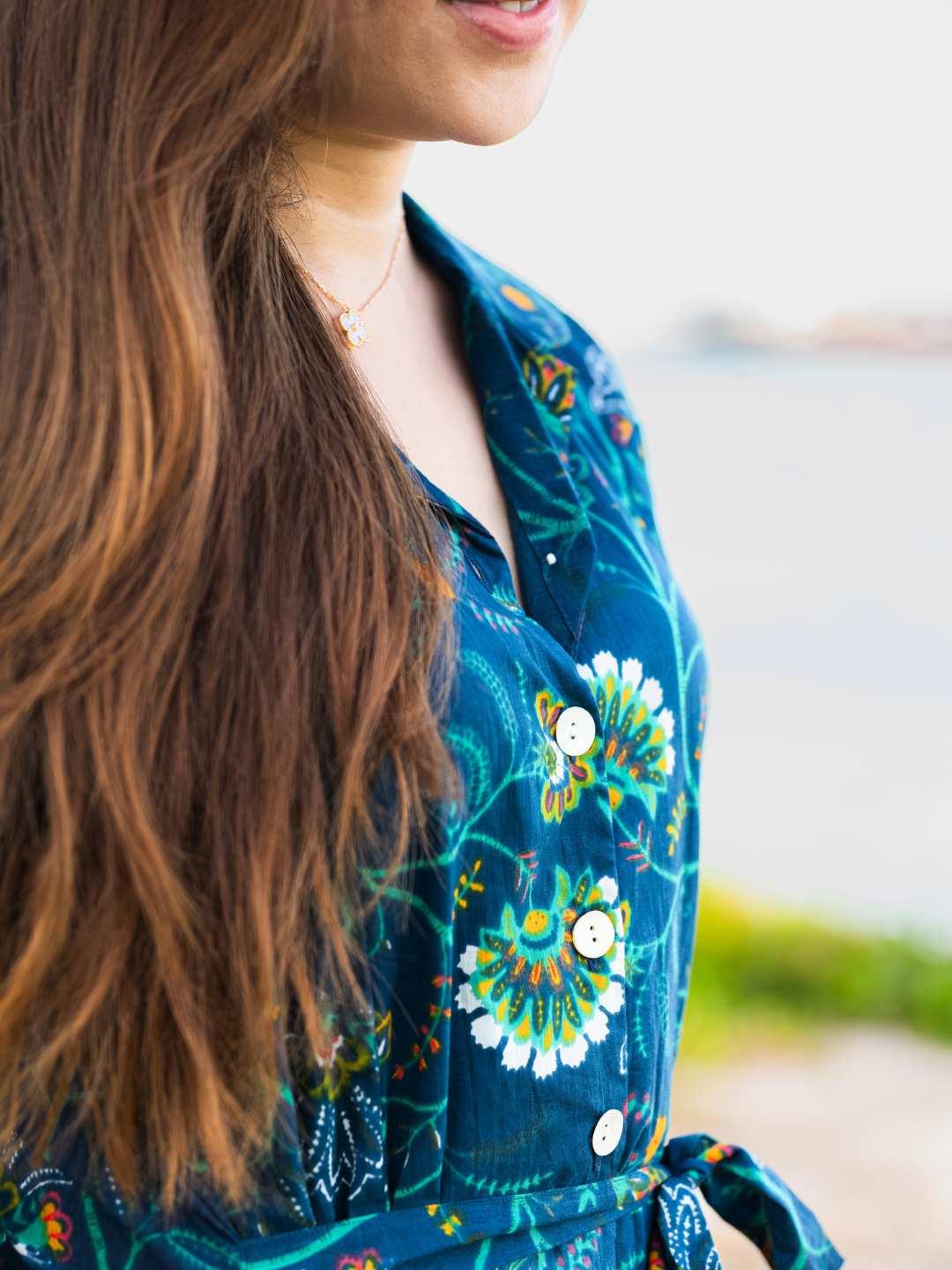 Woman wearing a blue floral dress with a blurred outdoor background
